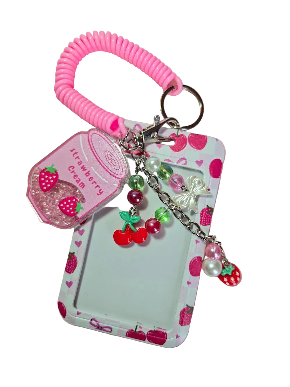 A pink coiled cord keychain with a clear plastic bag filled with strawberry-shaped beads and a white card holder decorated with pink strawberry illustrations, hanging on a white background.